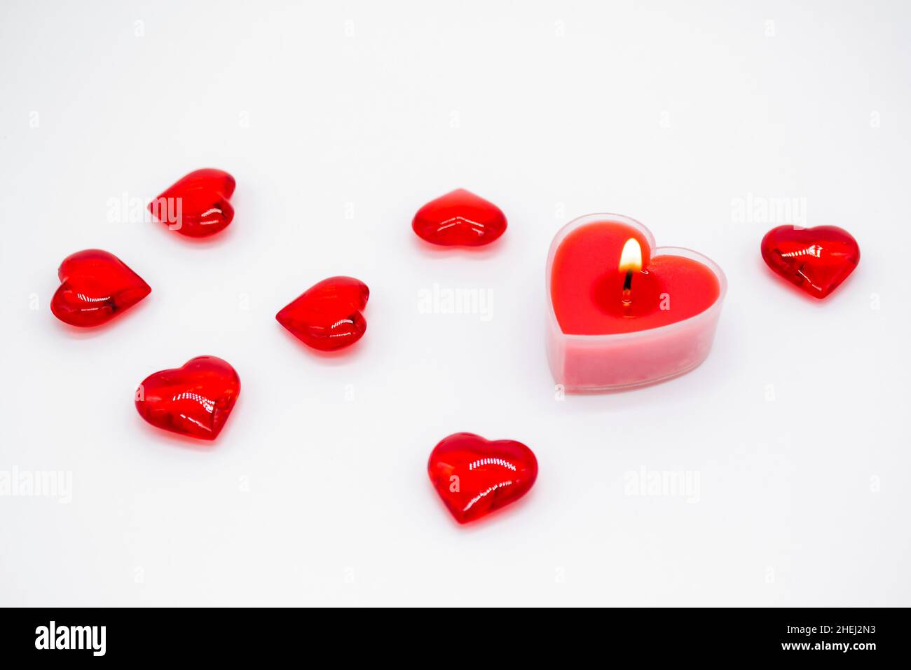 Une bougie rouge en forme de coeur brûle, et des coeurs de verre sont  couchés autour.Concept d'amour, Saint-Valentin, passion Photo Stock - Alamy