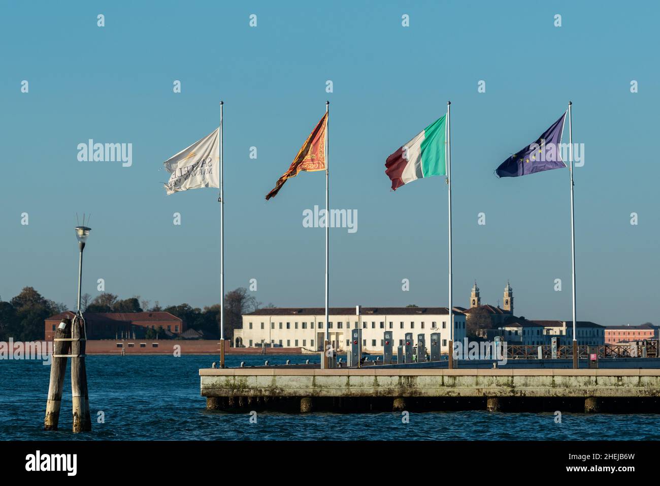 Drapeaux sur un quai à Venise (Italie) lors d'une journée ensoleillée et venteuse en hiver Banque D'Images