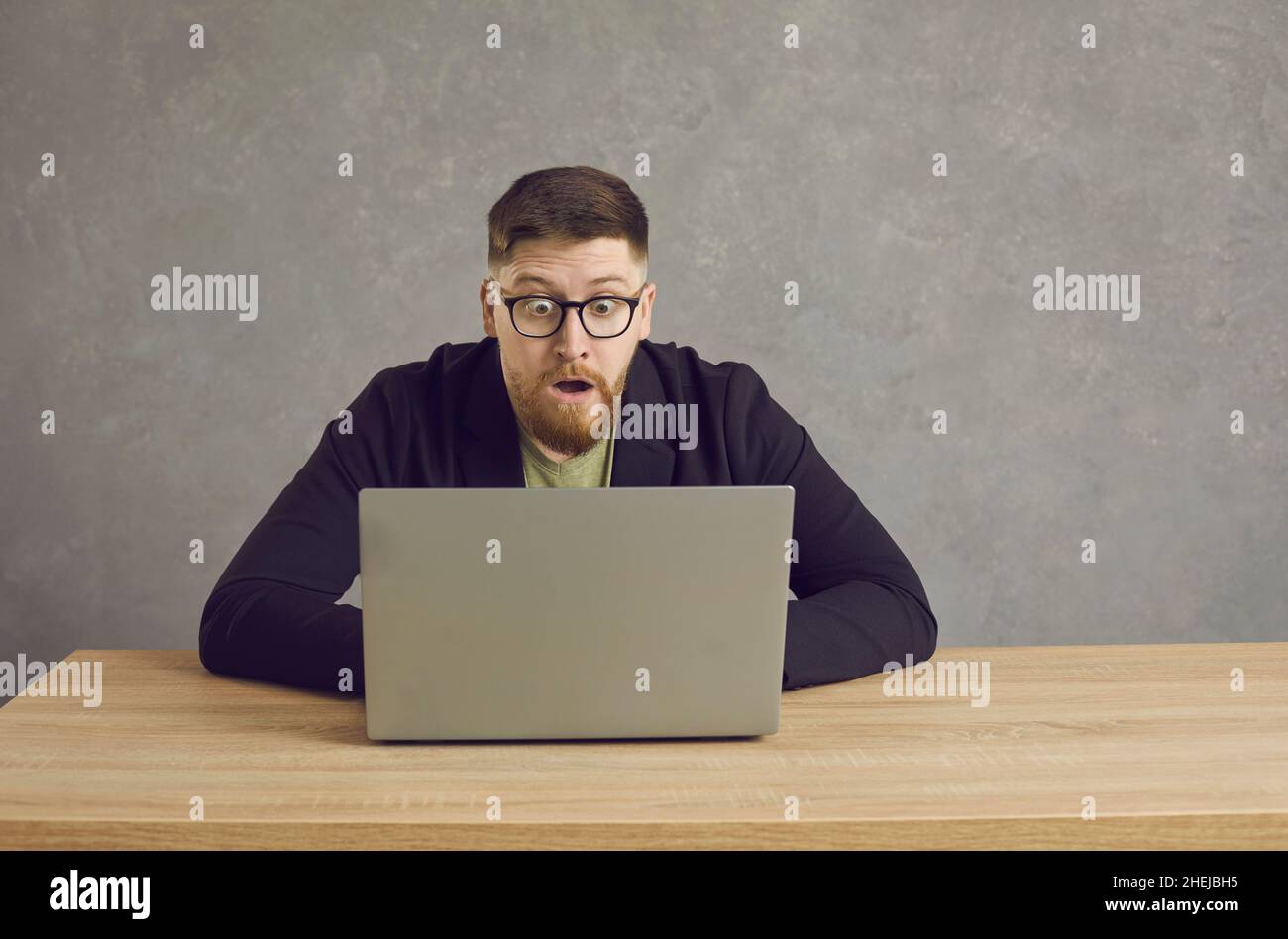 Homme caucasien avec une expression choquée, perplexe et effrayée regardant l'écran d'ordinateur portable. Banque D'Images