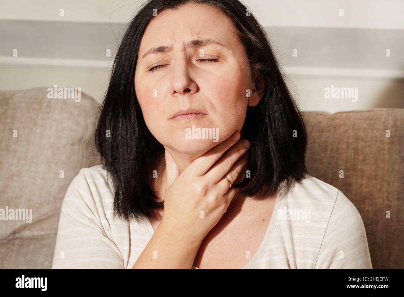 Femme mature touchant son cou.Une femme malade ressent des maux de gorge, de toux, de pharyngite et de enrouement.Trouble thyroïdien.Soins médicaux et de santé. Banque D'Images