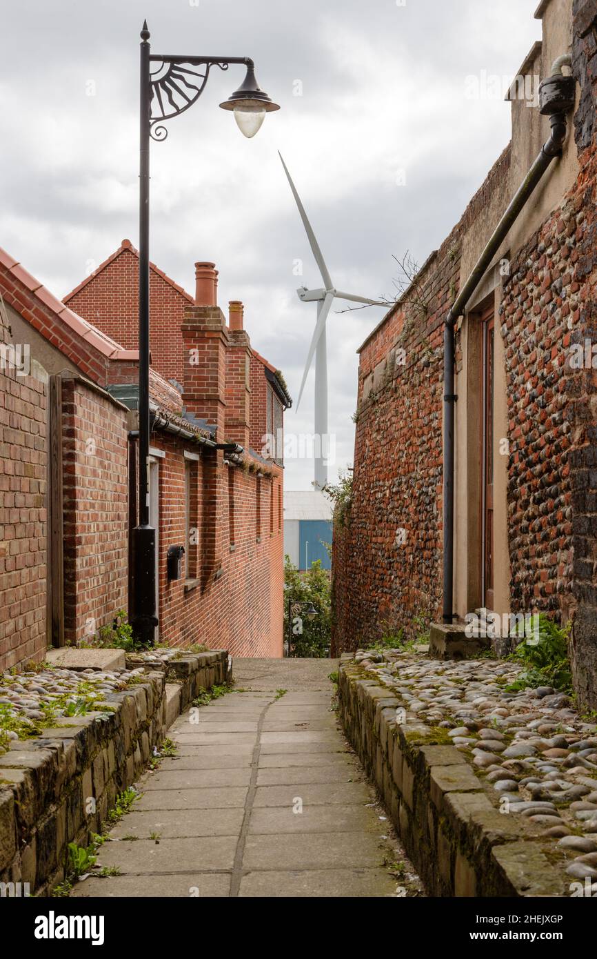 Lampe de rue à l'ancienne dans une allée entre les habitations avec un générateur d'électricité d'éolienne moderne situé sur la propriété industrielle. Banque D'Images