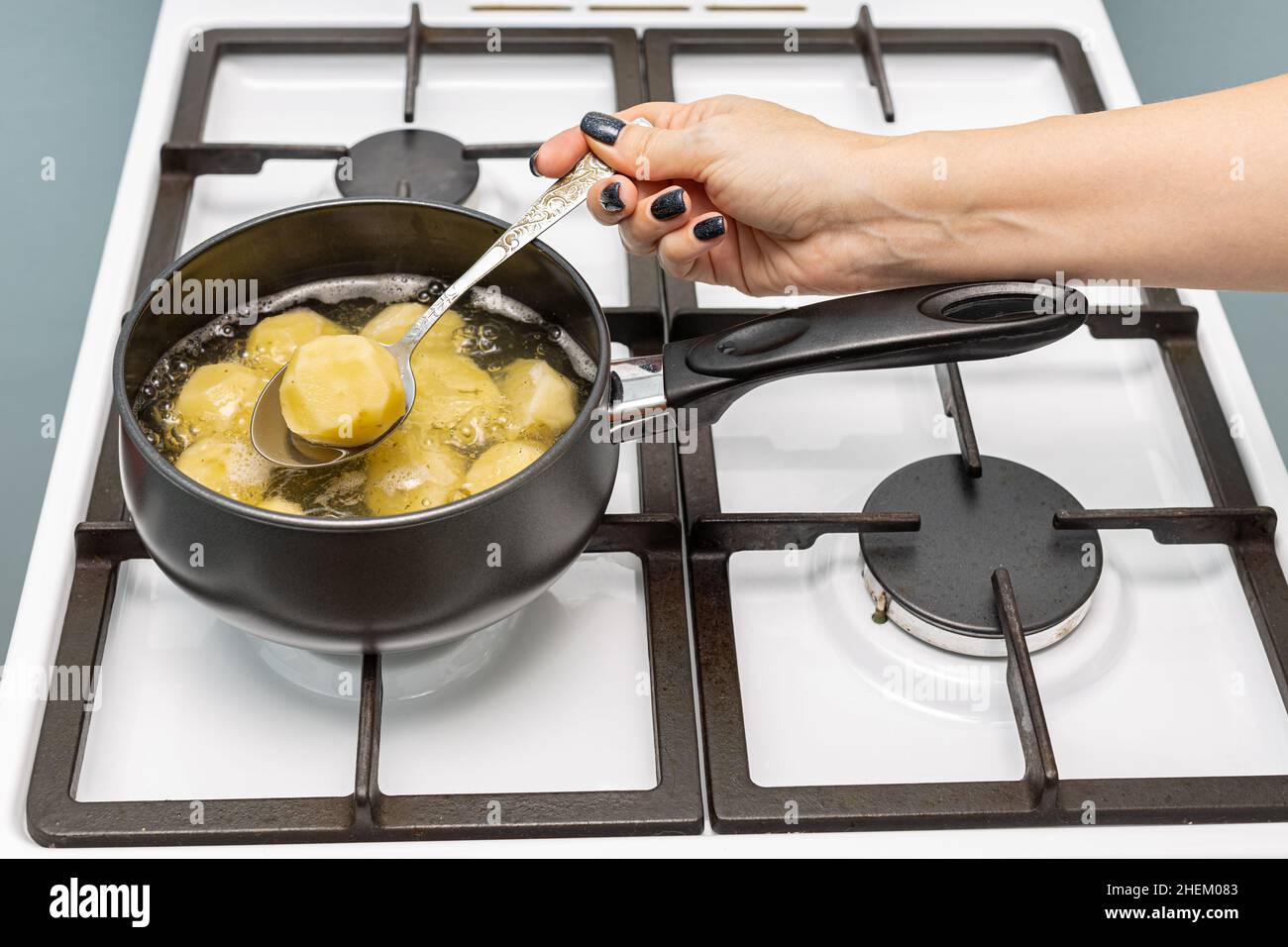 la main d'une femme sort une pomme de terre bouillie d'une casserole.Photo de haute qualité Banque D'Images