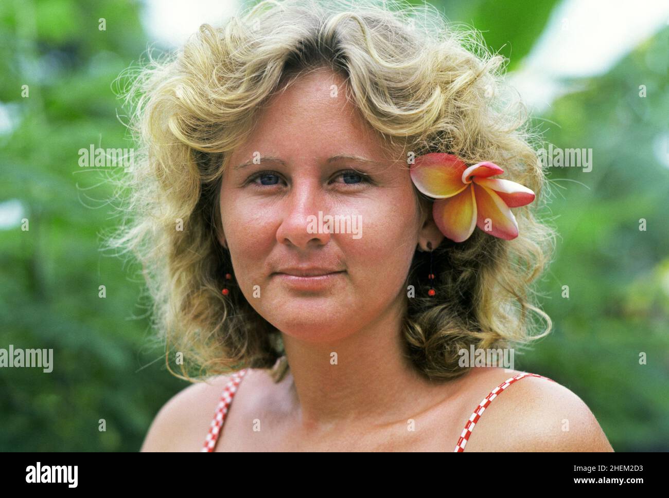 Le beau visage d'une fillette seychelloise avec une fleur frangipani derrière son oreille dans le parc national de la Vallée de Mai , sur l'île de Praslin, l'île des palmiers, dans les îles seychelles, dans l'océan Indien au large de la côte est de l'Afrique. Banque D'Images