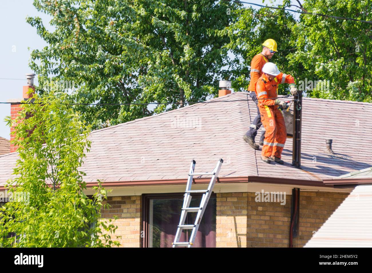 Toronto, Canada, 2015: Les travailleurs qui fixent des fils électriques à un poteau au-dessus d'une maison. Banque D'Images