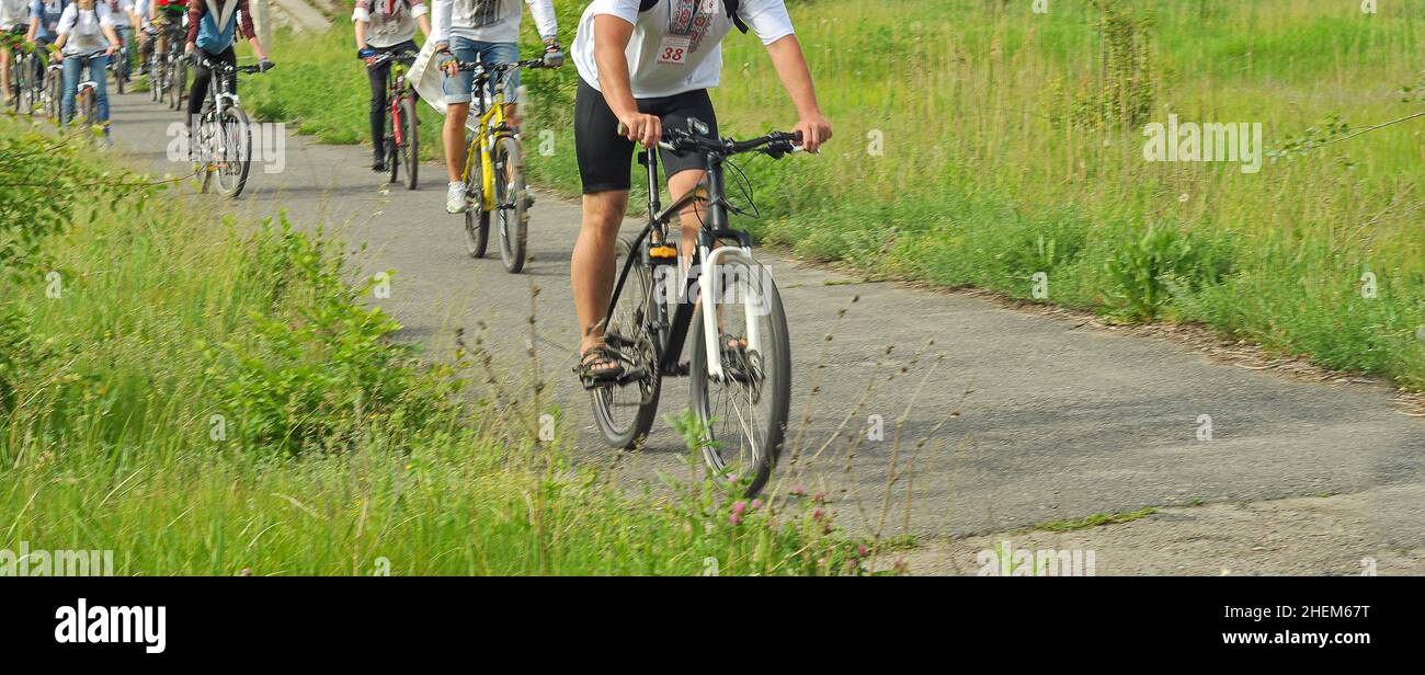 City bike Ride en Ukraine, les gens sans visage dans les vêtements décontractés, chemin d'asphalte et herbe verte. Banque D'Images