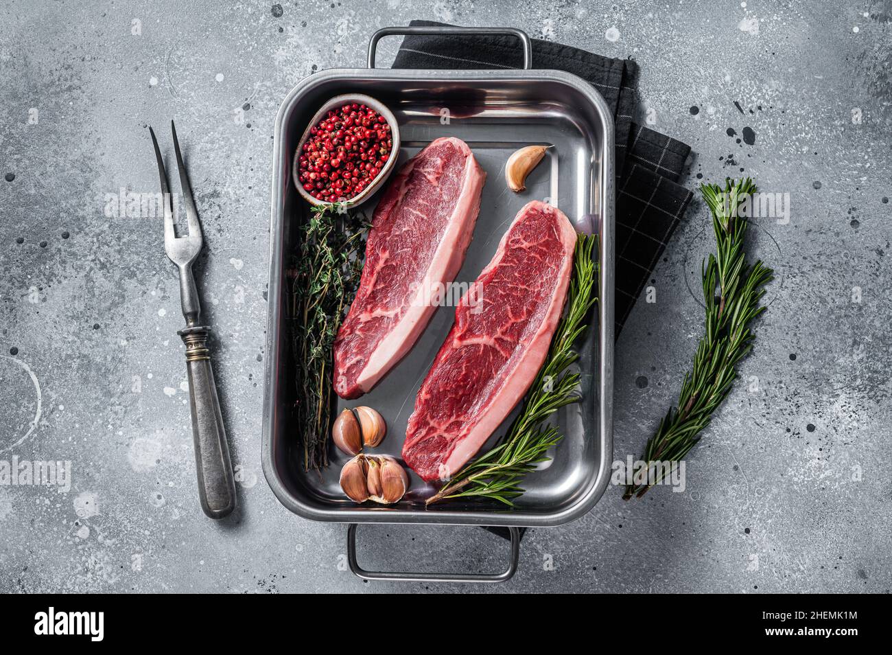 Bœuf de bœuf haché cru ou steak de bœuf de bœuf haché dans le plateau avec des herbes.Arrière-plan gris.Vue de dessus Banque D'Images