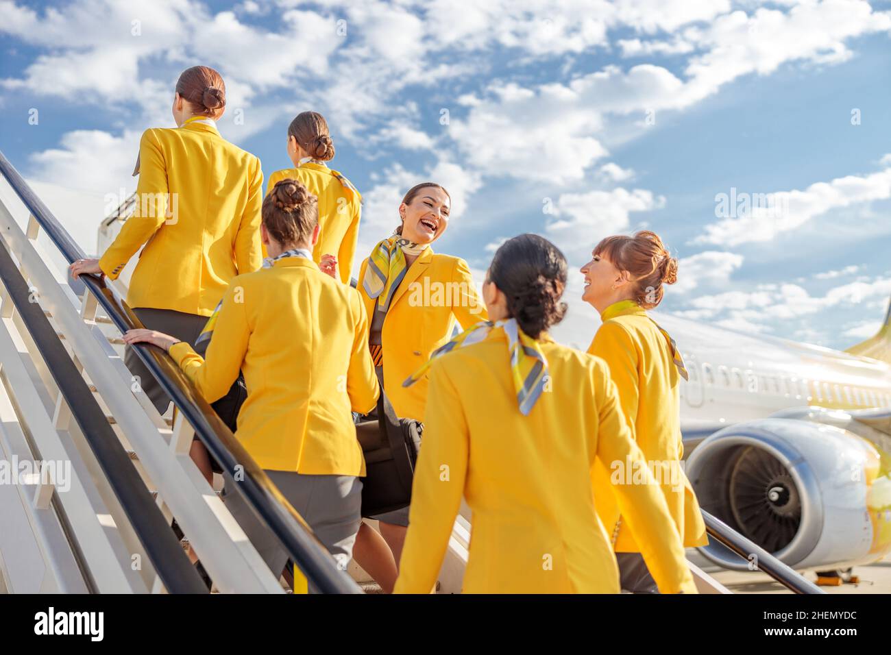 Groupe de femmes hôtesses portant des vestes jaunes debout sur les escaliers de l'avion Banque D'Images