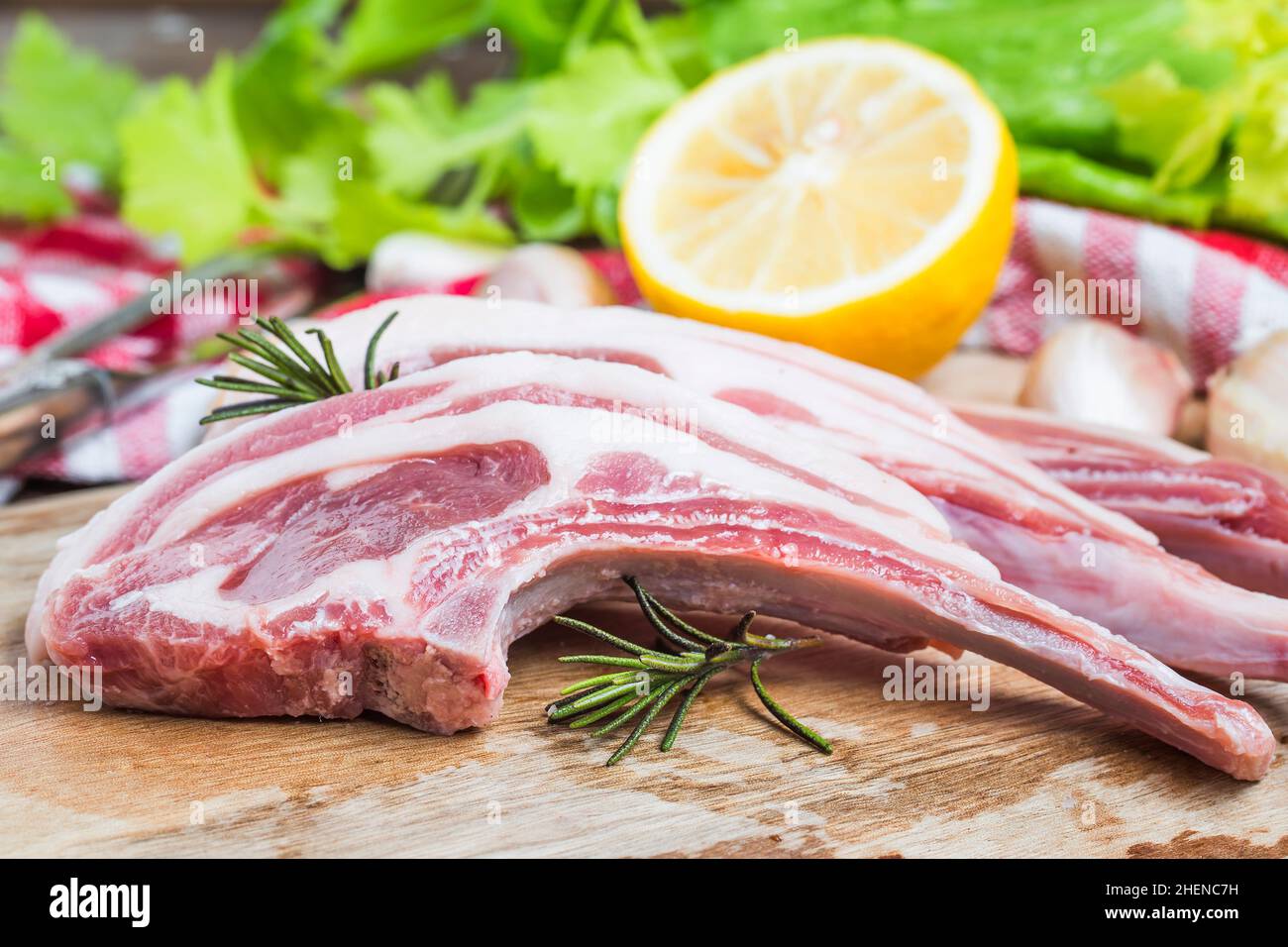 Côtelettes d'agneau brutes avec épices et herbes à gros plan sur fond en bois Banque D'Images