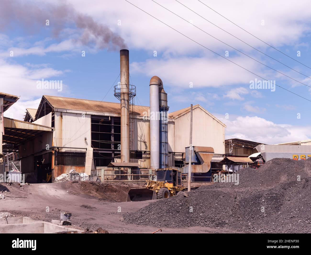 Tas de charbon utilisé pour produire de la vapeur avec des chaudières dans une usine industrielle.Cheminée de la chaudière en arrière-plan. Banque D'Images