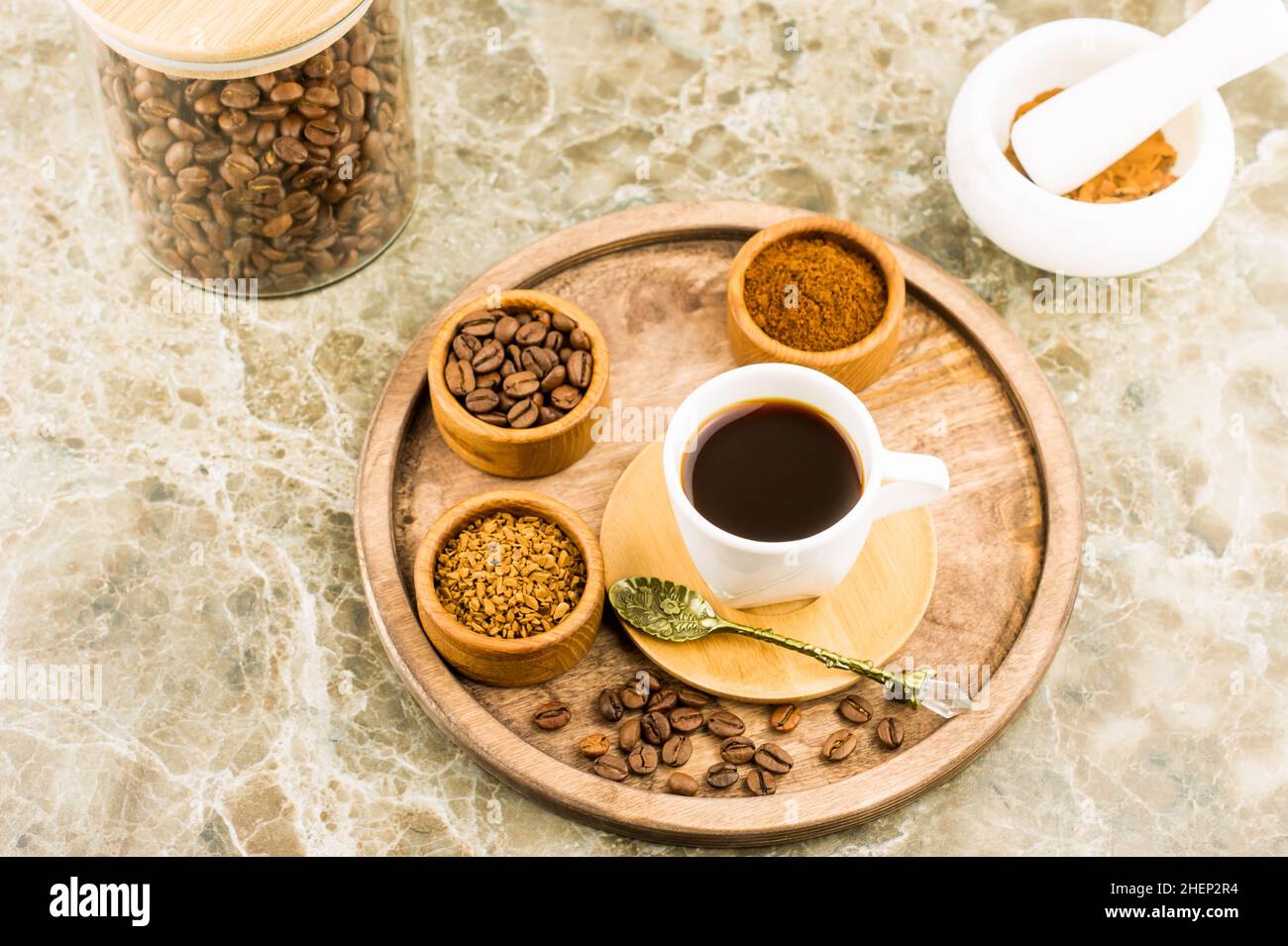 plateau rond en bois avec une tasse de café, des grains de café et du café lyophilisé dans des bols. bol en verre avec grains de café, mortier pour broyage Banque D'Images