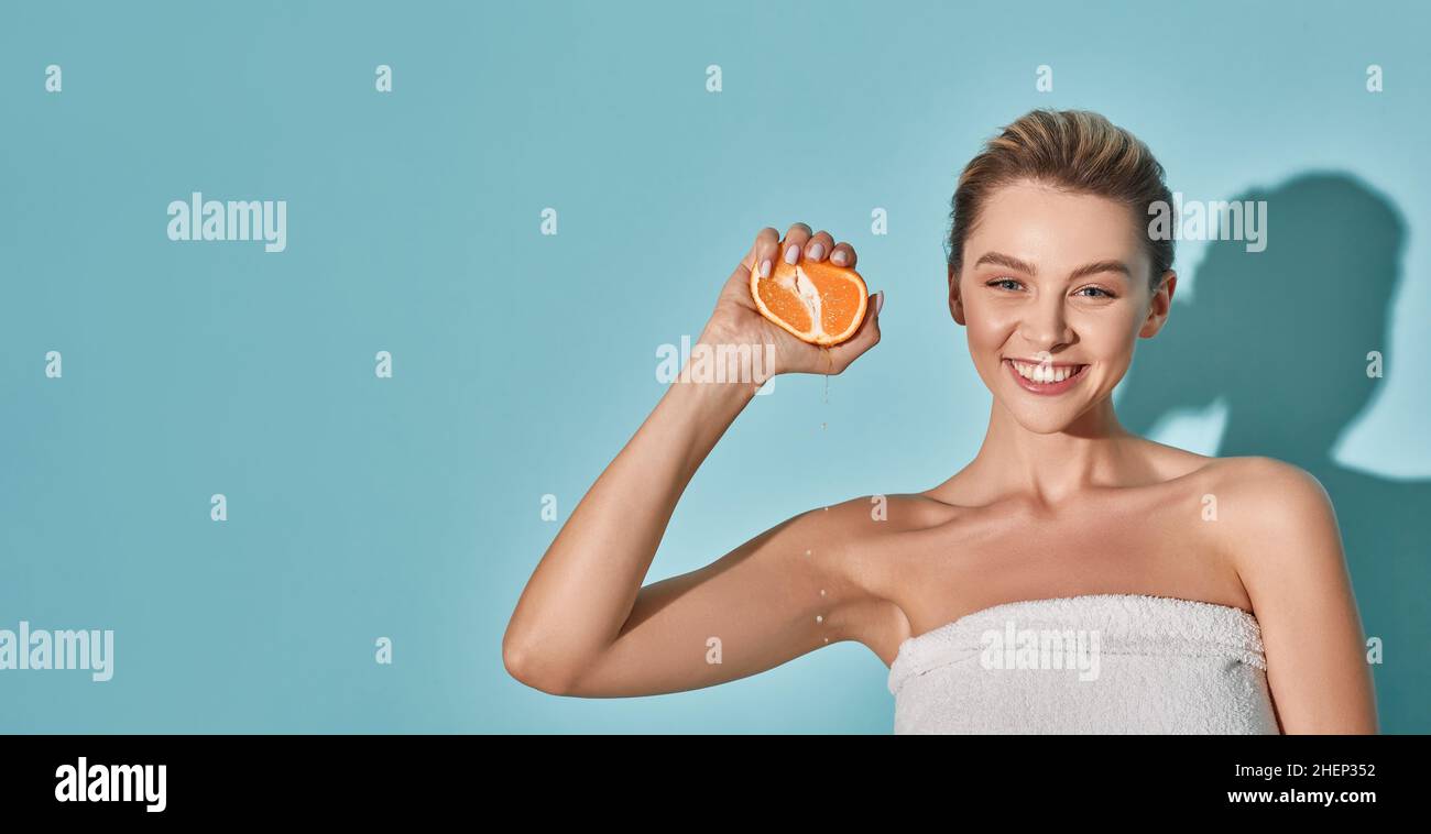 Cosmétiques avec vitamine C pour hydrater la peau.Bonne jeune femme avec une peau parfaite qui resserrant l'orange près de son visage.Concept de soins de la peau Banque D'Images