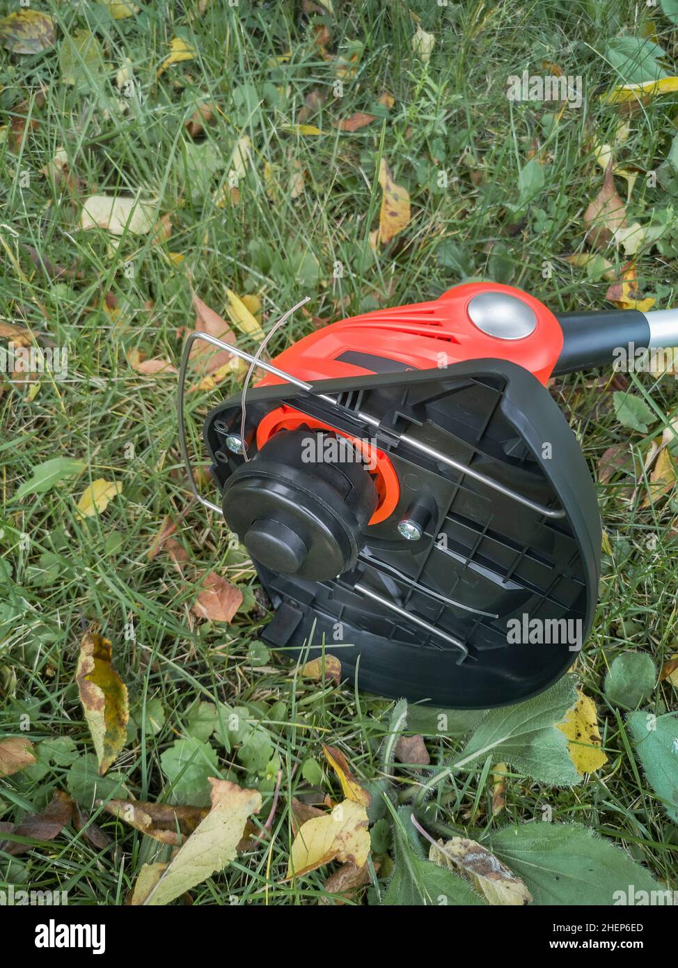 Appareils électroménagers : tondeuse-tondeuse pour couper des pelouses sur des batteries rechargeables.Présenté sur un fond d'herbe et de feuilles, vue avant, Banque D'Images
