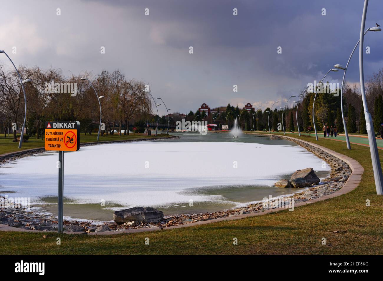 Lac artificiel partiellement gelé et fontaine à un parc de la ville et orange pas de signe de natation Banque D'Images