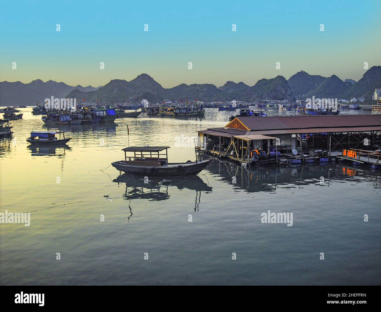 Coucher de soleil pittoresque avec des gens de bateau vivant sur des bateaux à moteur au Vietnam Banque D'Images