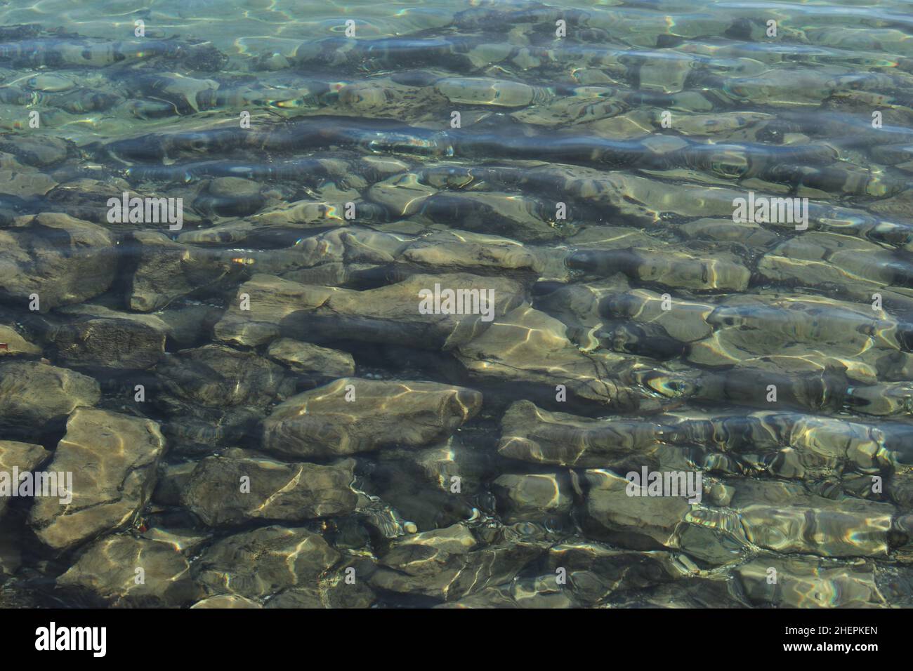Arrière-plan de pierres brillantes sur un fond de lac clair.Motif abstrait de grandes pierres grises sous la surface de l'eau turquoise (Lac de Genève) Banque D'Images