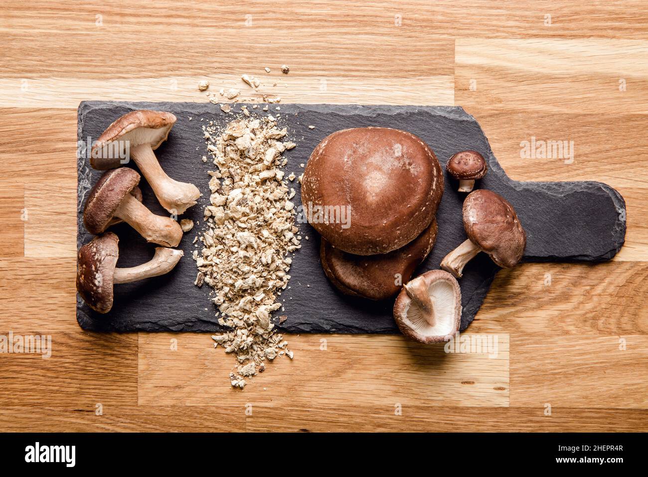 Plan de pose vue de la poudre sèche faite de champignons shiitake, Lentinula edodes.Ingrédient alimentaire sur planche à découper en pierre noire avec champignons shiitake frais. Banque D'Images Plan de pose vue de la poudre sèche faite de champignons shiitake, Lentinula edodes.Ingrédient alimentaire sur planche à découper en pierre noire avec champignons shiitake frais. Banque D'Images