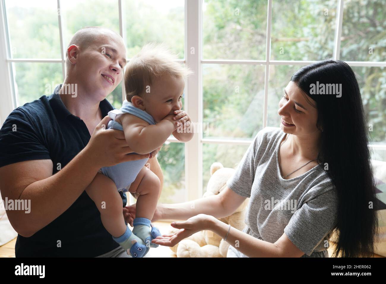 Jeune couple avec un bébé jouant et assis sur le seuil de la fenêtre dans une nouvelle maison Banque D'Images