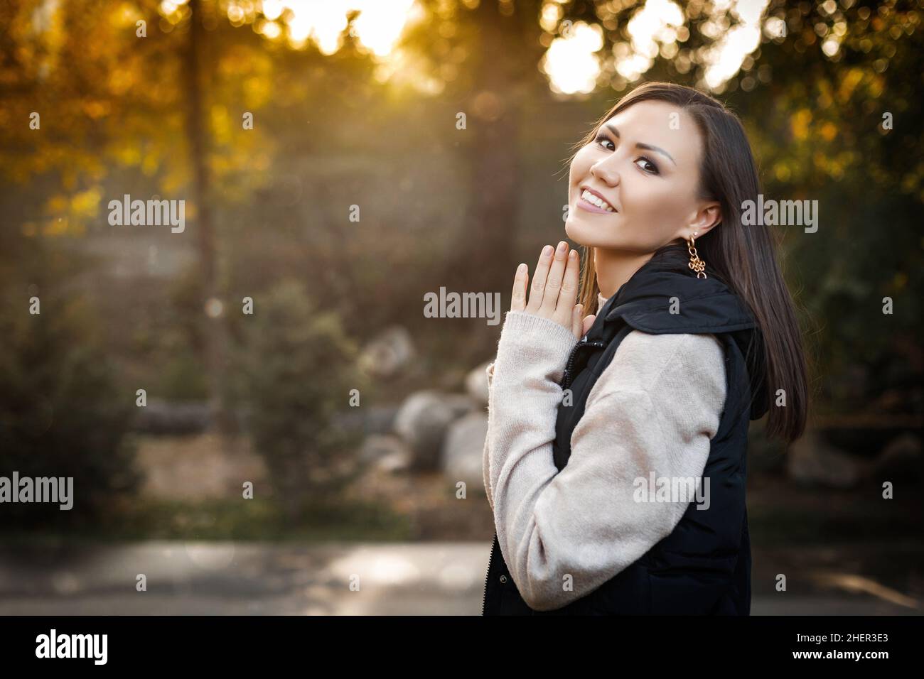 Une jeune femme souriante sur le côté droit de la photo se tient dehors en automne dans un pull chaud et une veste sans manches.Photo de haute qualité Banque D'Images