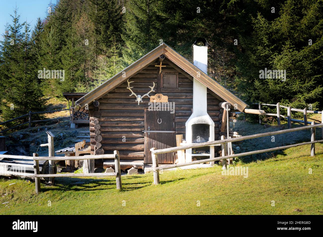 ancienne cabane en bois avec bois de cerf et cheminée en brique dans le défrichement de la forêt Banque D'Images