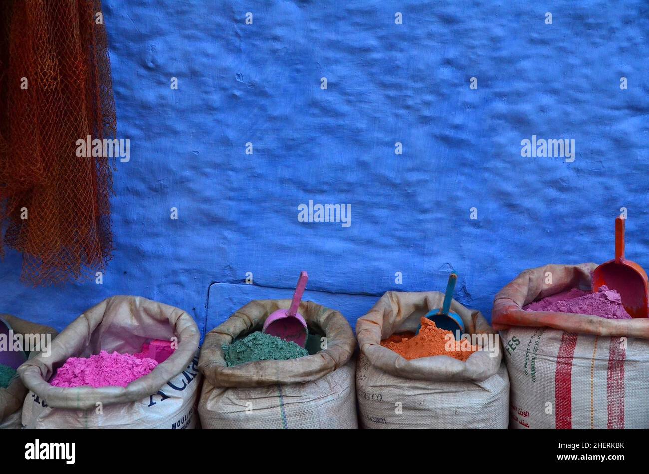 Poudre de peinture colorée en sacs devant le mur bleu avec pelle, Chefchaouen, Maroc Banque D'Images