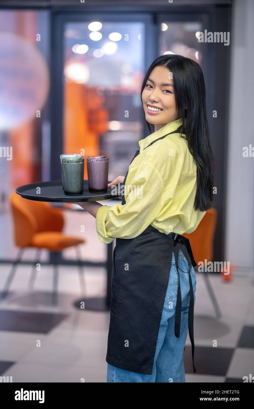 Serveuse asiatique jeune avec un plateau entre les mains Banque D'Images