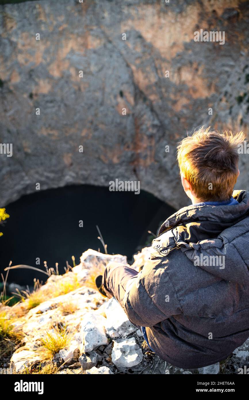 Homme blond jouissant d'une vue sur le lac rouge en avril à Imotski, Dalmatie, Croatie Banque D'Images