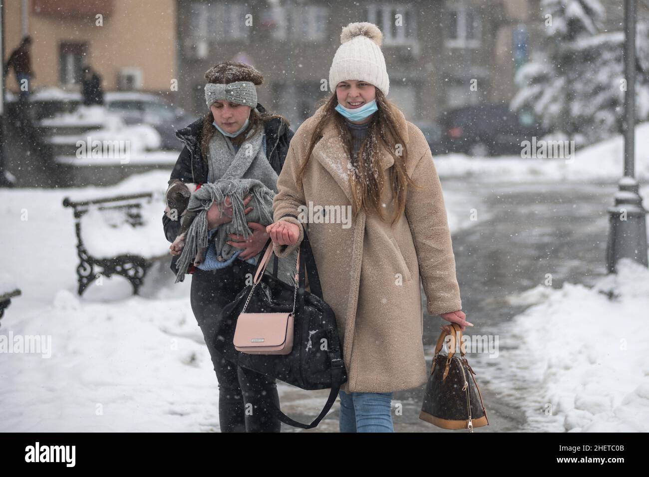 Hiver en Serbie : deux femmes avec masque facial portant un chiot pitbull dans le parc Saint Sava, Belgrade Banque D'Images