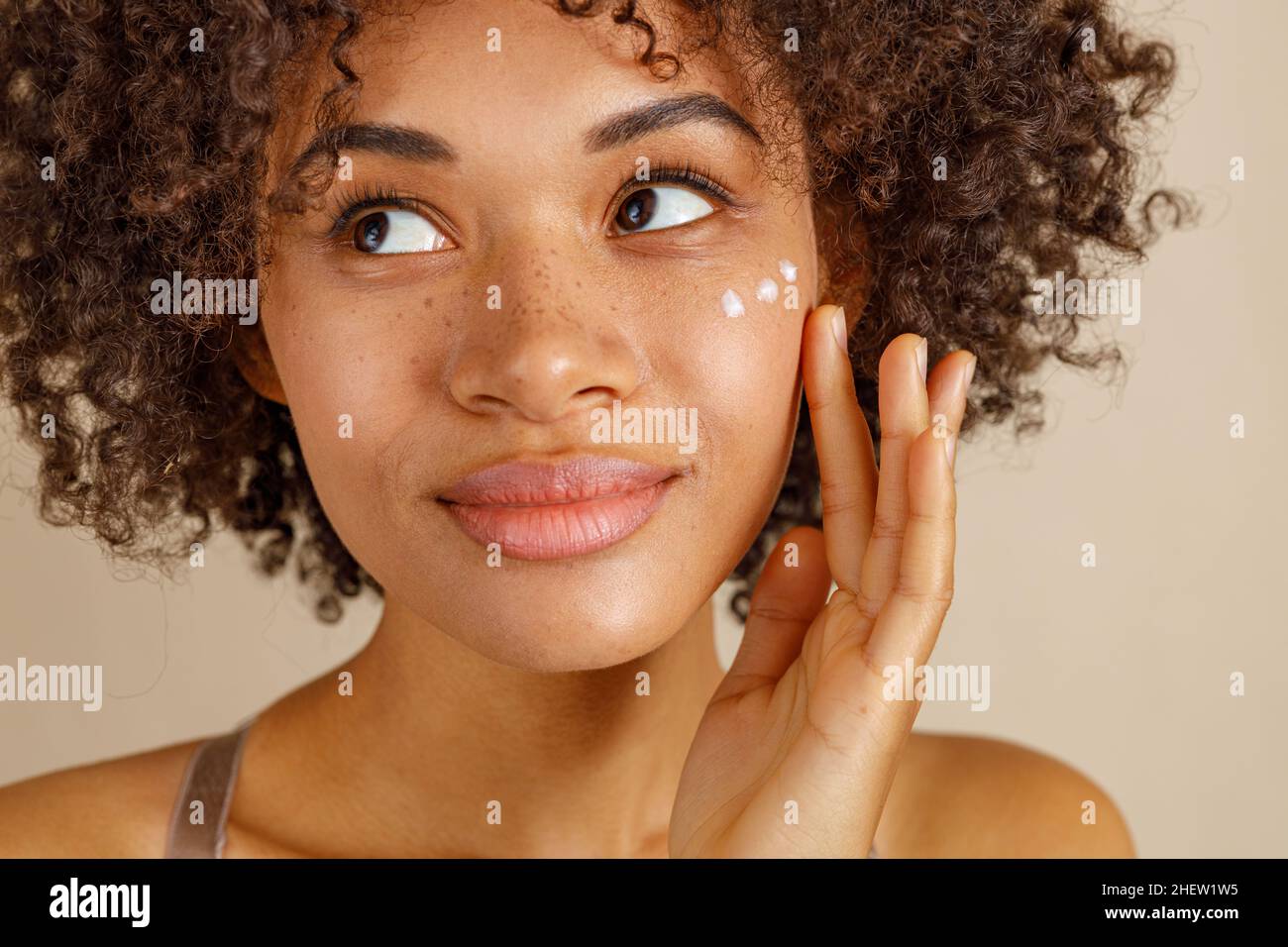Jolie dame utilisant des produits cosmétiques en studio Banque D'Images