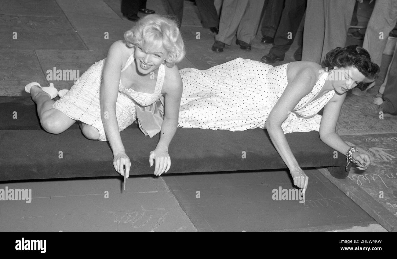 Les actrices Marilyn Monroe et Jane Russell mettent des signatures, des empreintes de main et de pied en béton humide au Grauman's Theatre, 1953 Banque D'Images
