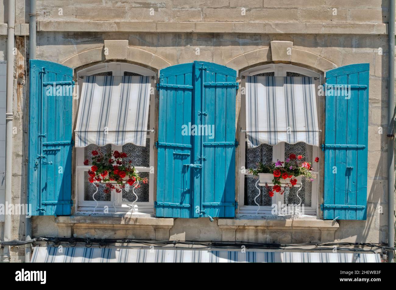 Les fenêtres avec volets et les plantes en pot font un écran coloré. Banque D'Images