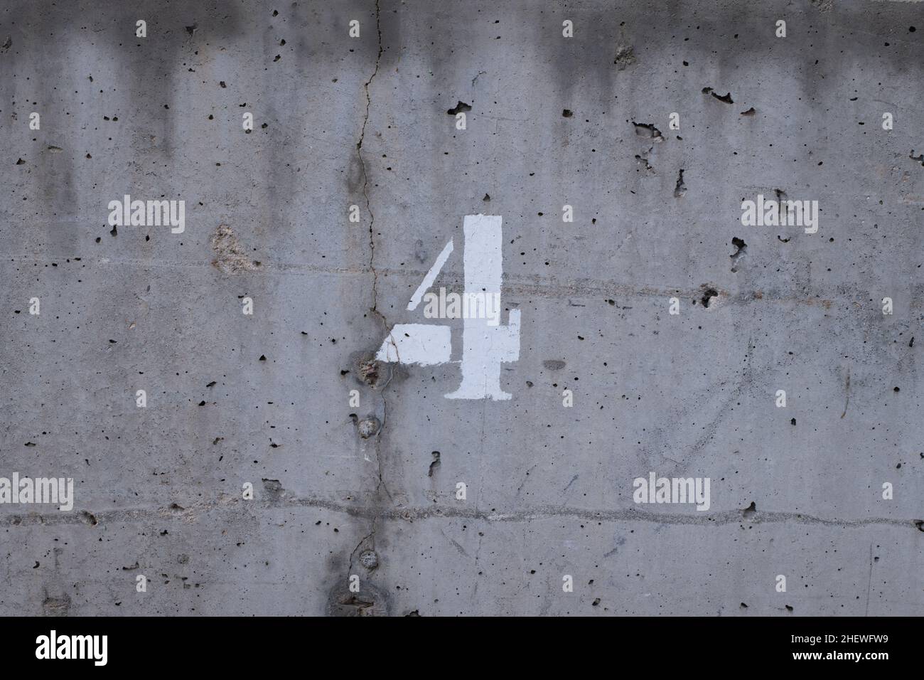 numéro quatre sur un mur en béton avec des points noirs et une fissure Banque D'Images