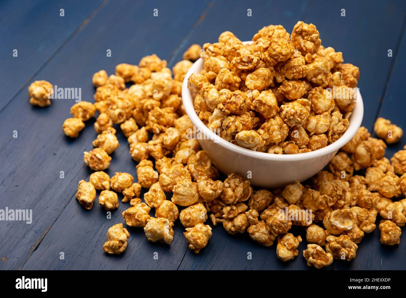 Popcorn caramel dans un bol blanc sur une table en bois bleu rustique.Gros plan.Copiez l'espace pour votre texte Banque D'Images