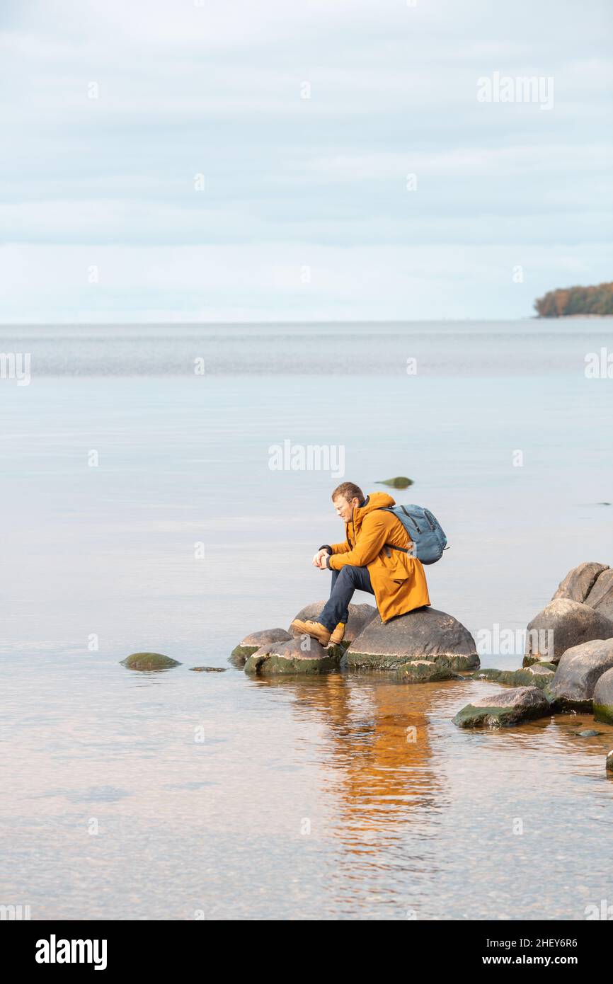 Homme caucasien assis sur le rocher en face du lac et appréciant la vue.Homme se reposant après une longue marche Banque D'Images