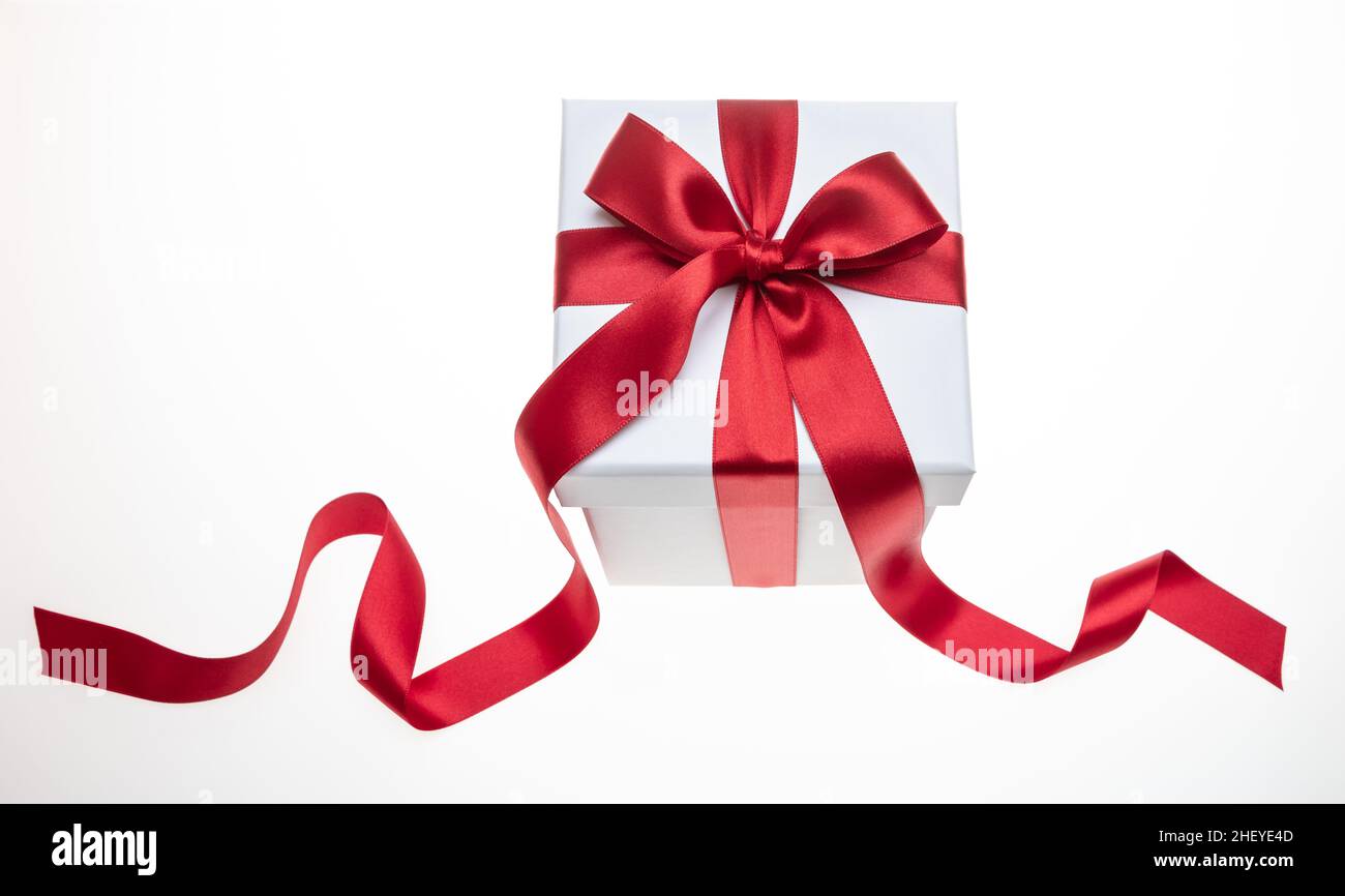 Boîte cadeau ruban rouge et noeud isolé sur fond blanc, cadeau de Noël Saint-Valentin, décoration en satin Banque D'Images