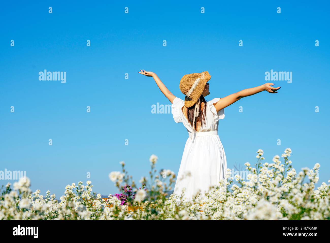 Bonne femme bras ouverts respire autour.Freedom Girl sautant et profitant de la vie contre le ciel bleu dans le jardin fleuri. Banque D'Images