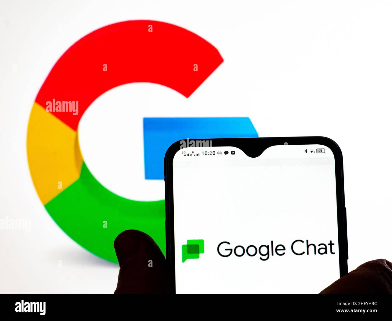 Dans cette illustration, le logo Google Chat s'affiche sur l'écran d'un smartphone et le logo Google en arrière-plan. Banque D'Images