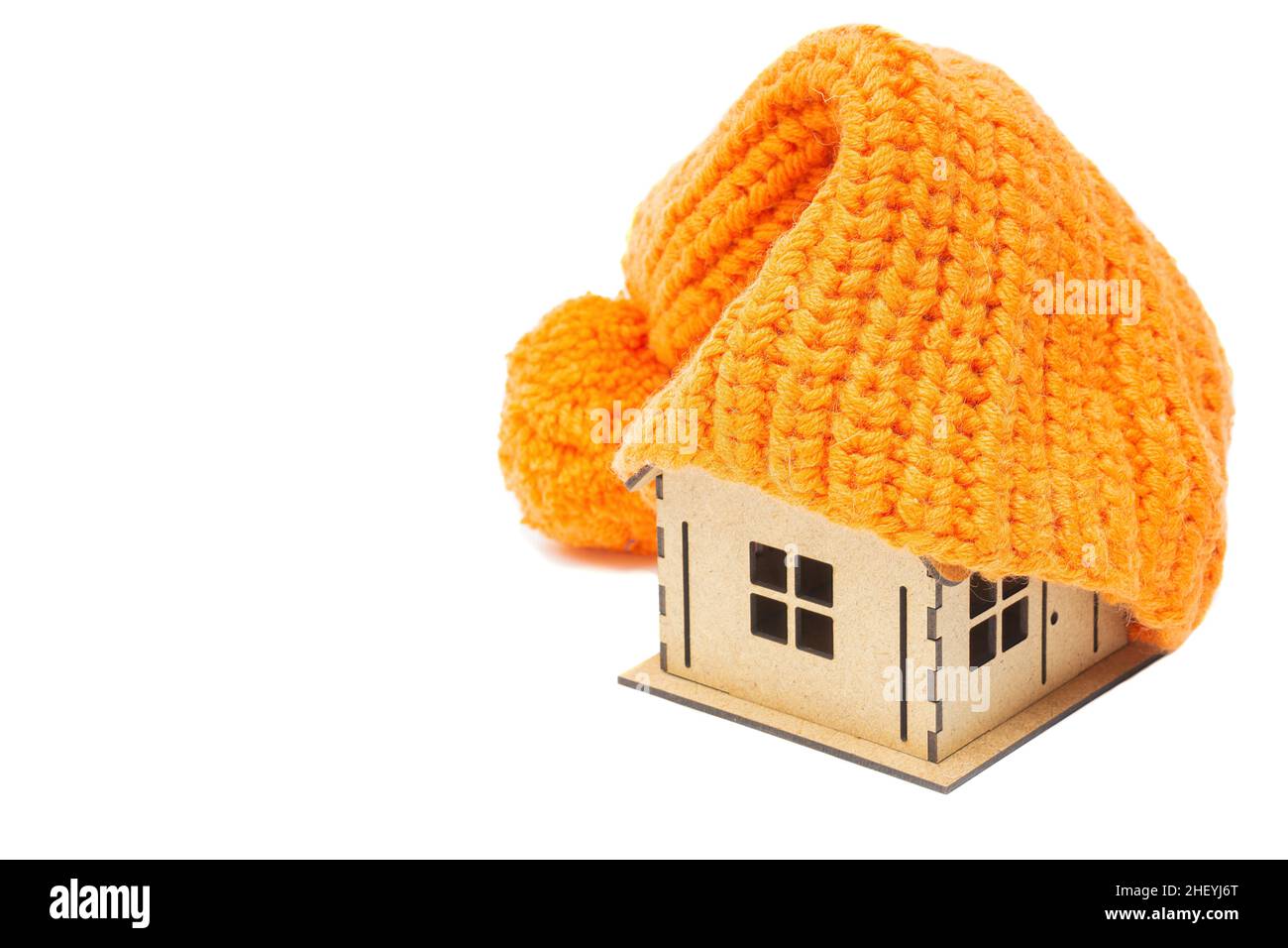 Chapeau orange chaud sur le dessus d'une maison de jouets isolée sur fond blanc.Concept d'isolation pour la maison résistant à l'hiver. Banque D'Images