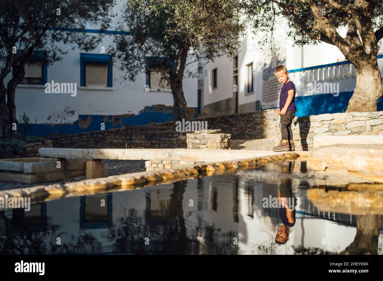 Un petit garçon qui profite d'une place historique avec une source d'eau à Ericeira, au centre du Portugal Banque D'Images