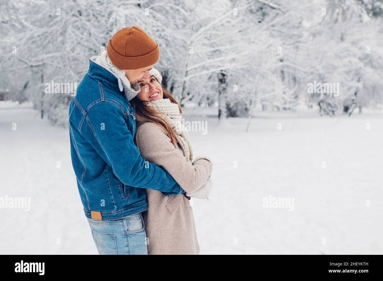 Date de la Saint-Valentin.Jeune couple aimant élégant marchant dans le parc d'hiver.Homme et femme qui s'embrasse en plein air en profitant d'un paysage enneigé Banque D'Images