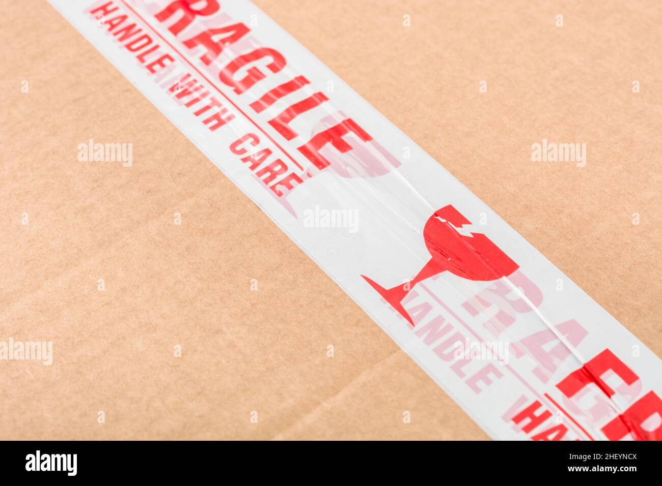 Boîte d'expédition en carton brun avec ruban adhésif « fragile Handle with Care » en polypropylène rouge et blanc.Pour quelque chose de fragile. Banque D'Images