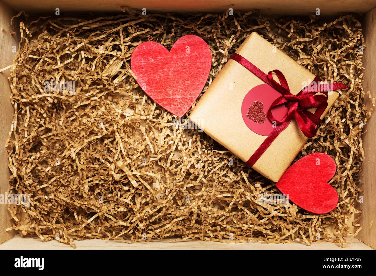 Boîte en bois avec cadeau emballée dans du papier brun artisanal avec ruban  rouge, remplie de papier de remplissage, vue de dessus Photo Stock - Alamy