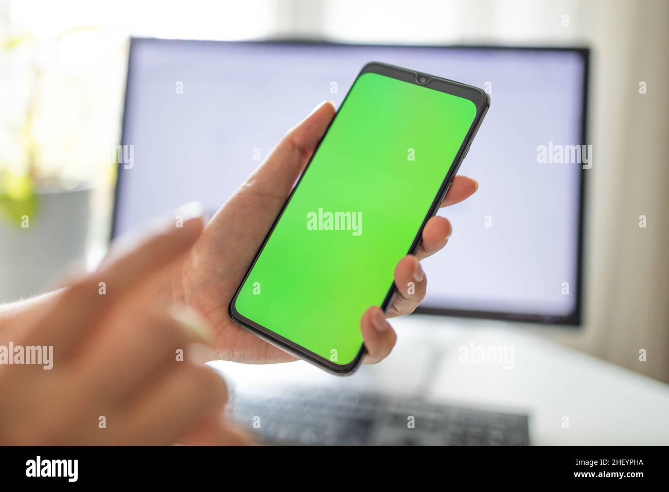 Smartphone avec écran vert vertical en tram chroma clé smartphone technologie téléphone cellulaire dans les mains de femme.Main avec écran de téléphone portable Banque D'Images