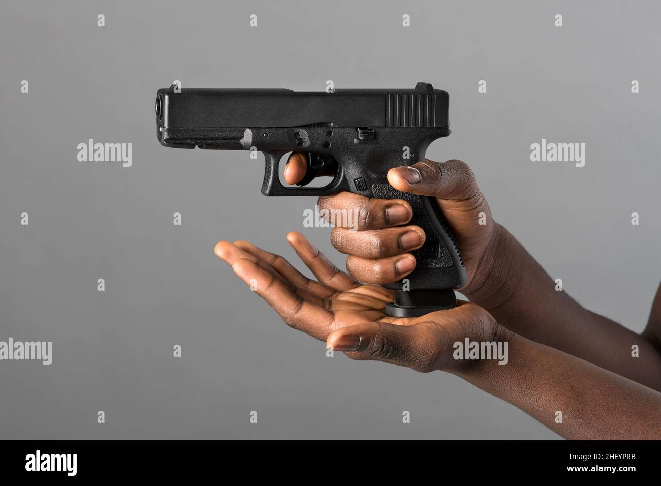 Mains d'un Noir fermant un magazine chargé de munitions sur un pistolet en position de visée dans un concept de crime, de violence, d'application de la loi ou de sel Banque D'Images
