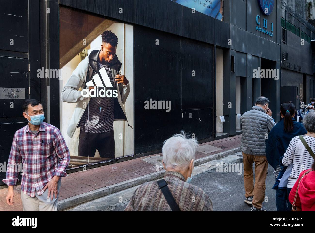 Des piétons marchent devant le magasin Adidas de la marque multinationale allemande de vêtements de sport à Hong Kong. Banque D'Images