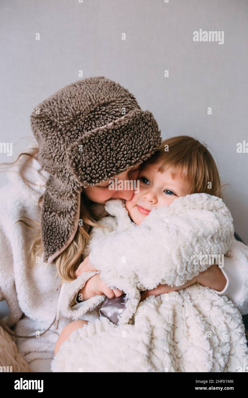 Maman et fille se câliner à la maison dans des vêtements chauds d'hiver Banque D'Images