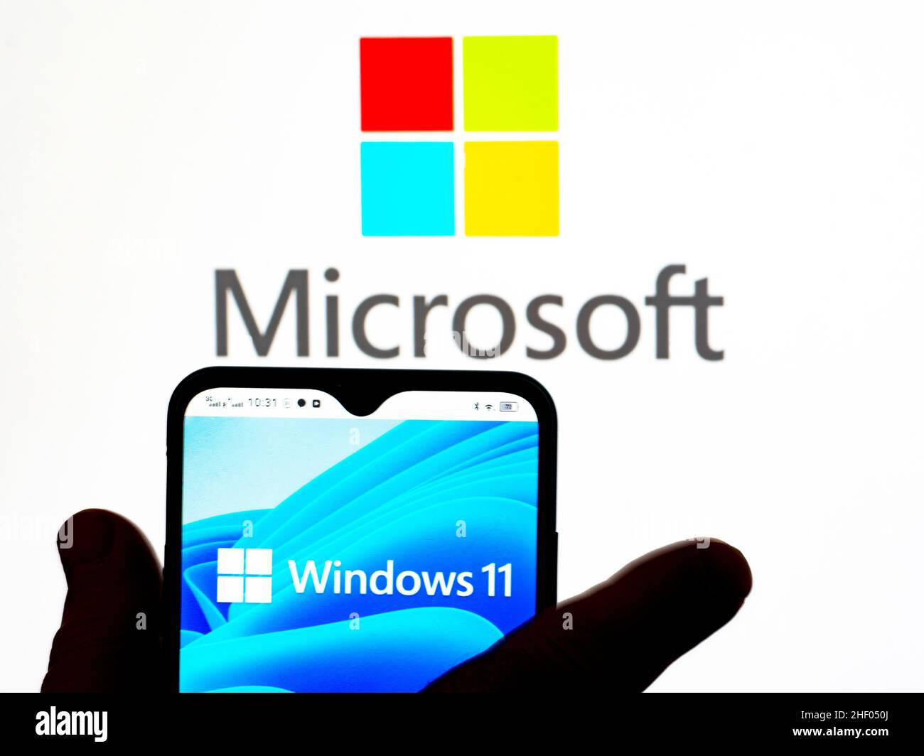 Dans cette illustration, le logo Microsoft Windows 11 s'affiche sur l'écran d'un smartphone et le logo Microsoft en arrière-plan. Banque D'Images