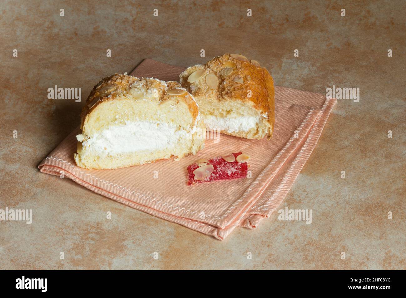 Morceau de fruits confits avec sucre glace sur une serviette élégante accompagné de décorations de gâteau traditionnelles remplies de crème et d'amandes sur un abstractl Banque D'Images