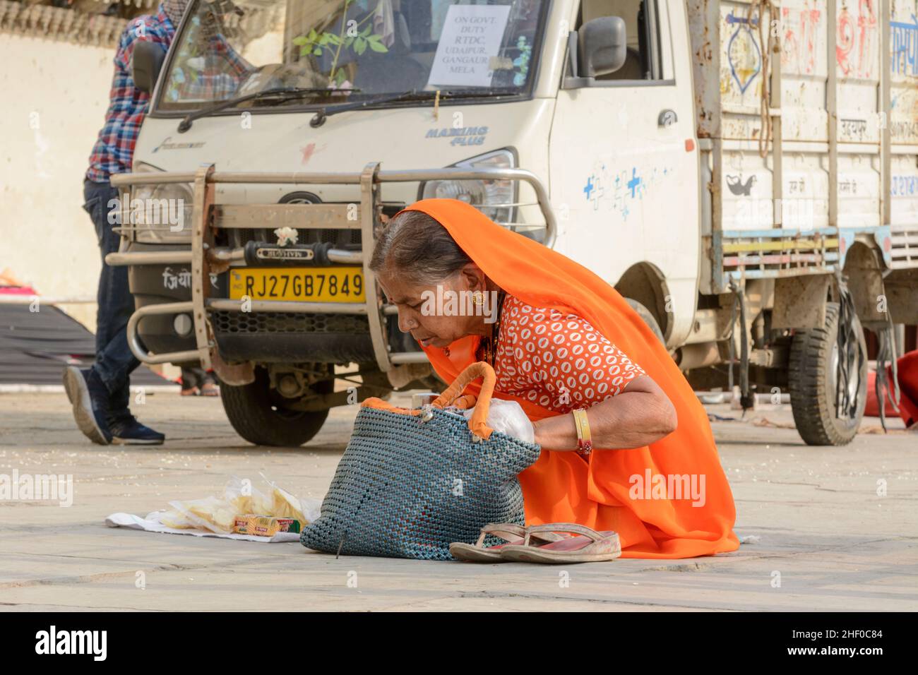 Une femme indienne âgée portant une orange sari vend des collations alimentaires aux touristes à Udaipur, Rajasthan, Inde, Asie du Sud Banque D'Images