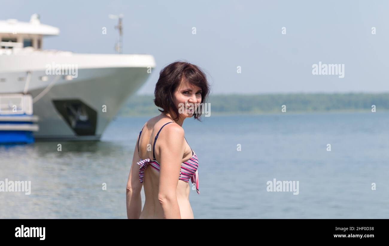 Une femme heureuse en maillot de bain entre pour la première fois dans l'eau glacée du lac Baikal. Banque D'Images