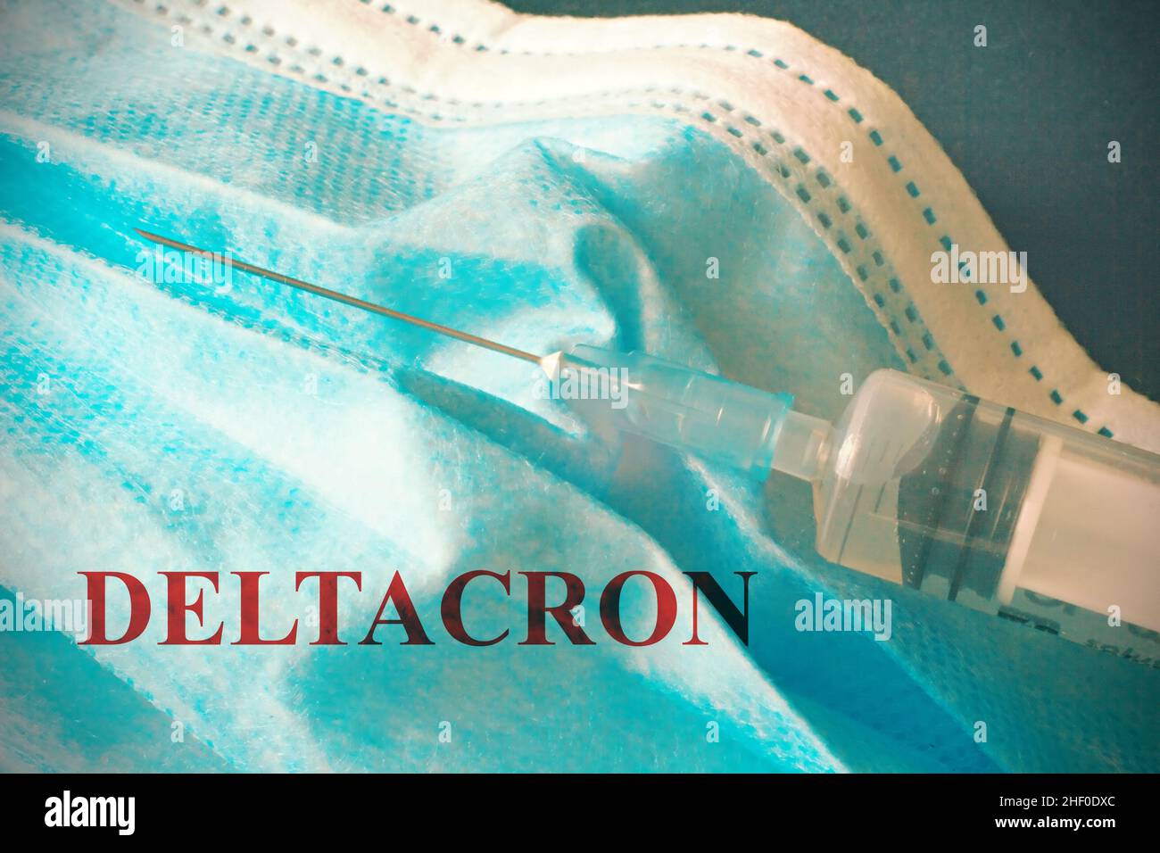 Vue de dessus d'une seringue reposant sur un masque chirurgical avec le texte « Deltacron » nouvelle variante Covid-19. Banque D'Images
